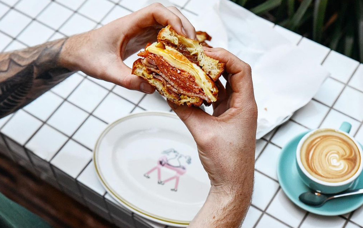 tattooed hands hold a breakfast sandwich