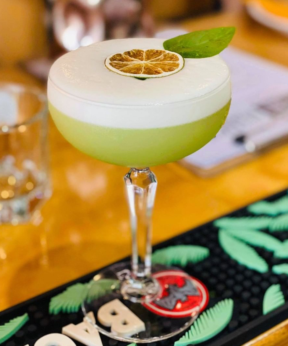 a lime coloured cocktail on a bar.