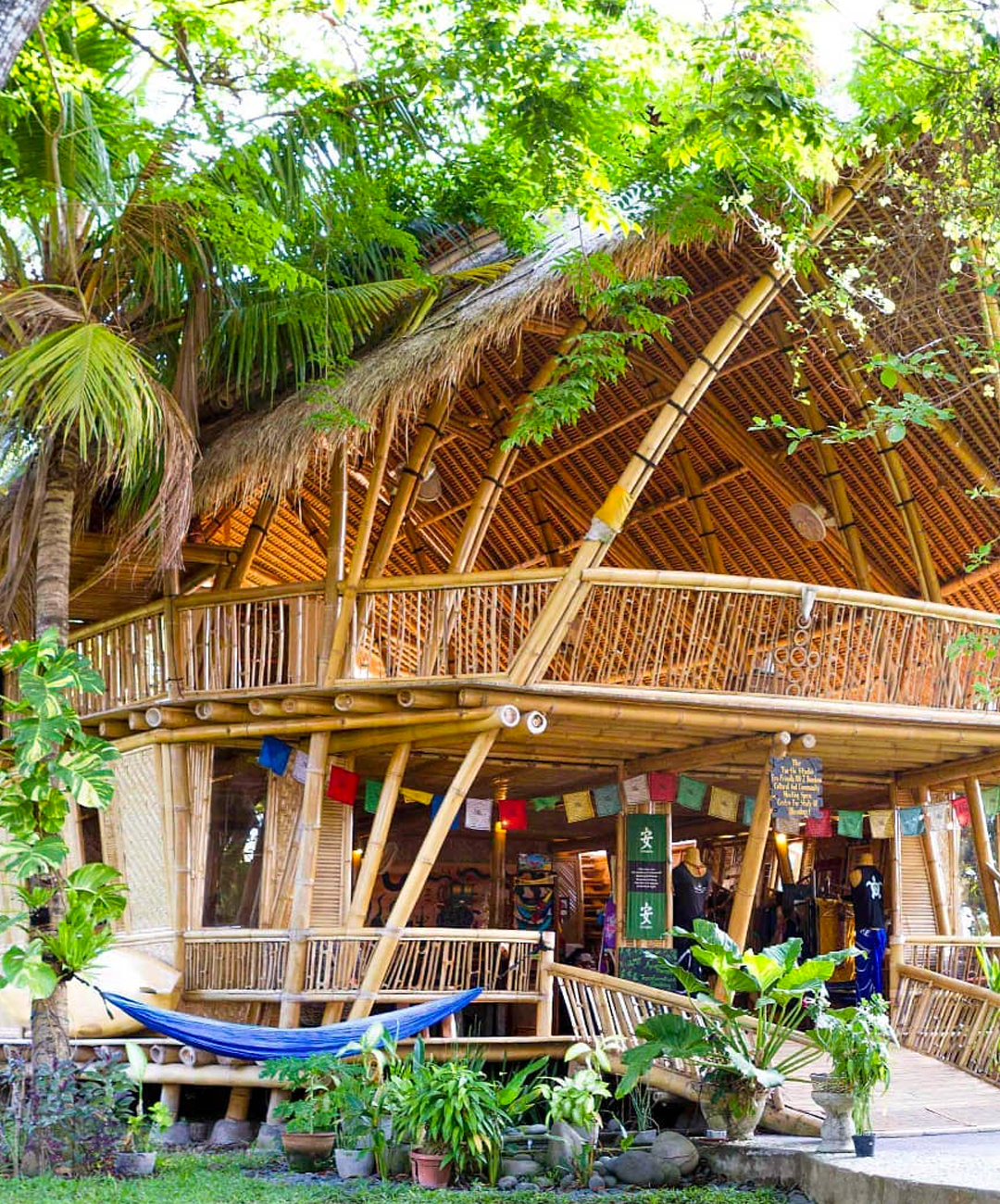 a bamboo hut with a hammock and rainbow flags