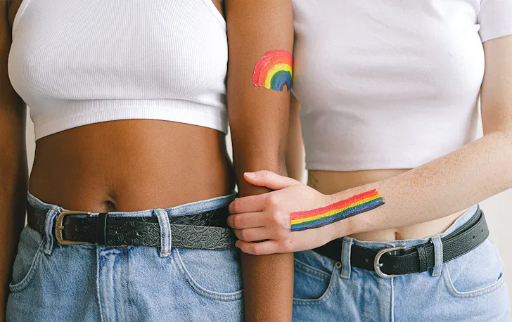 rainbows are painted on the arms of two people wearing denim jeans and white t-shirts