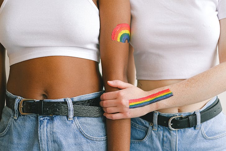 rainbows are painted on the arms of two people wearing denim jeans and white t-shirts