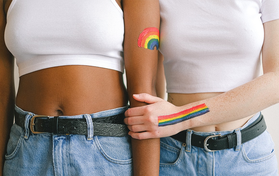 rainbows are painted on the arms of two people wearing denim jeans and white t-shirts