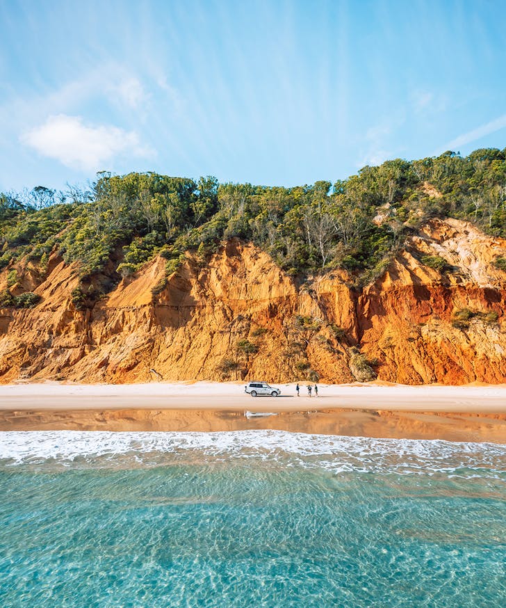 a car is parked on the golden sand of Rainbow Beach