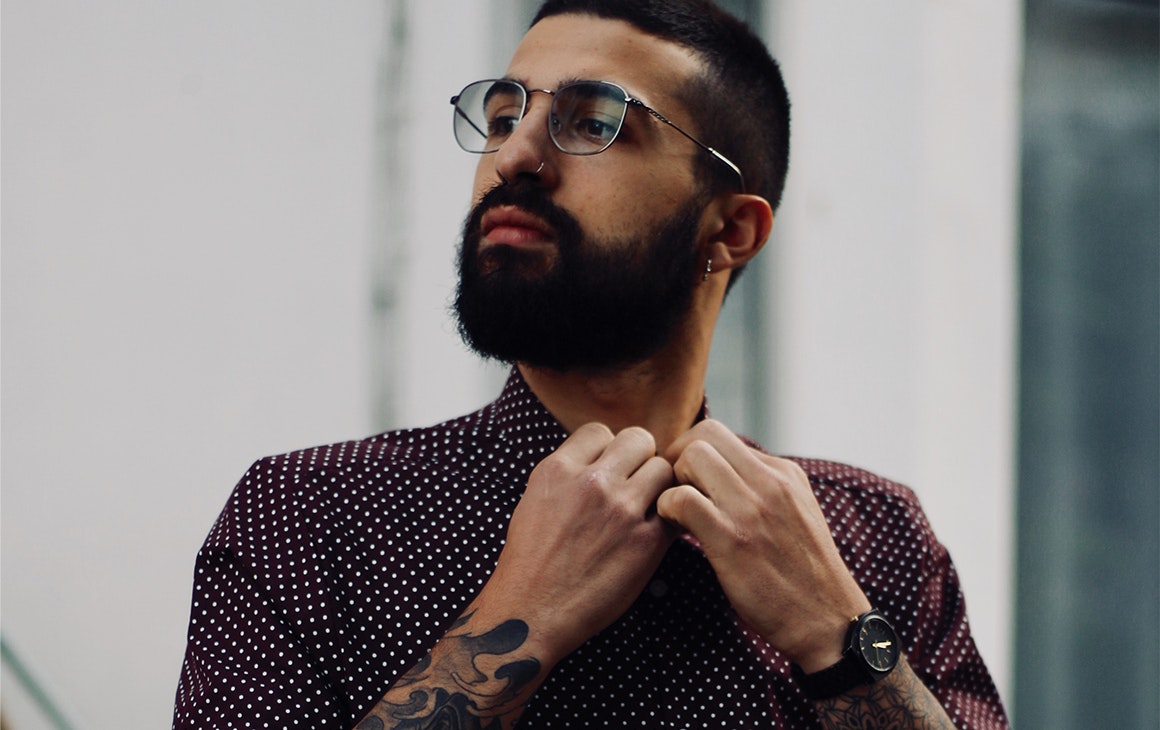 a young man wearing glasses, adjusts his collar.