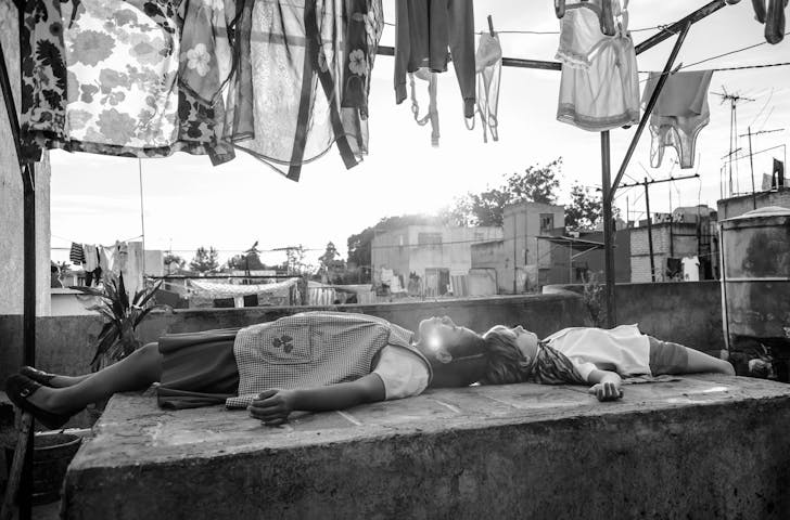 two young people lying on a ledge, washing hangs above them