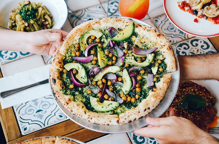 hand holding vegan pizza