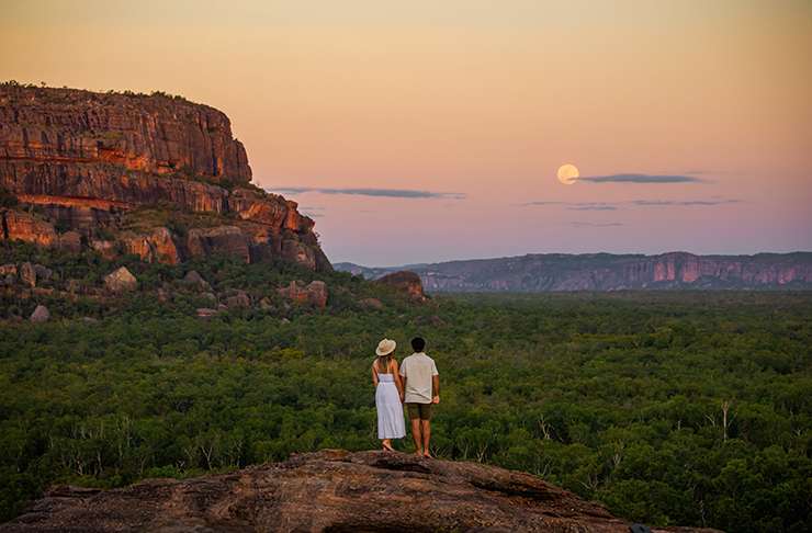 two people standing on rock in the northern territory with a full moon