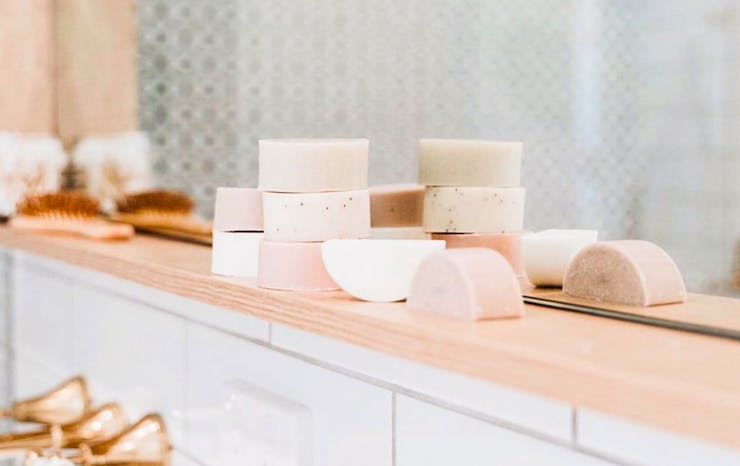 on a pale timber bench in a bathroom is a stack of shampoo bars