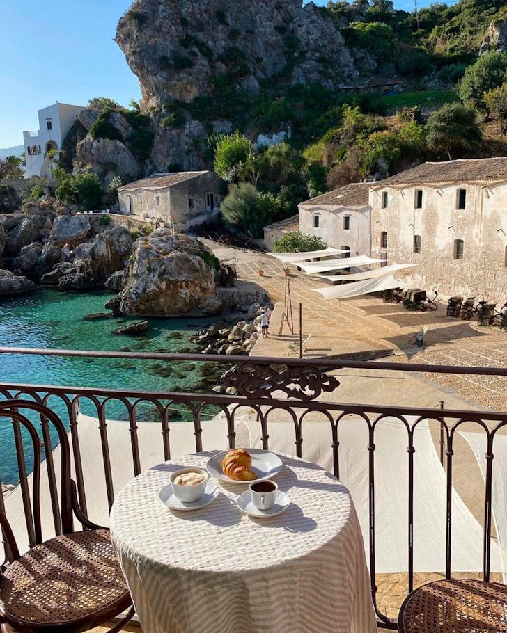 a small balcony overlooking a pebbly beach on a sunny day