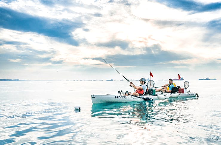 Two people kayaking with blue skies and clouds. 