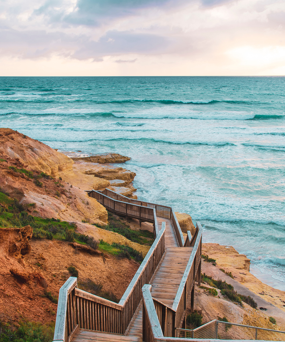 a set of stairs lead down to a beach at dusk.