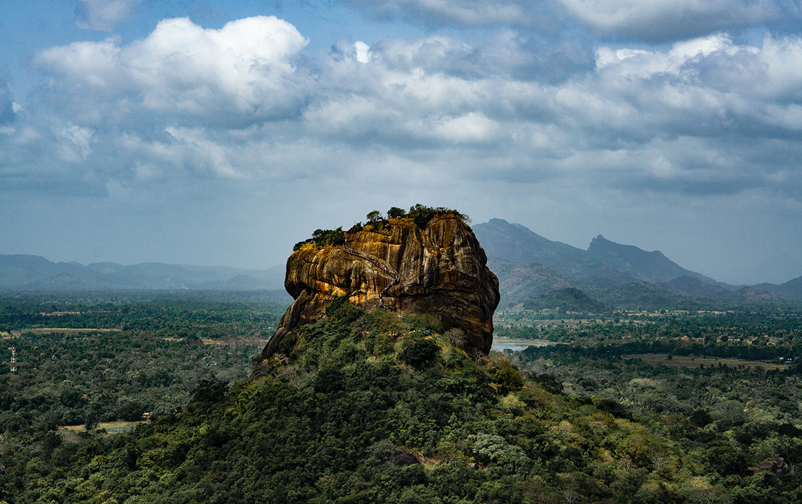 a large rocky formation stands out from clusters of trees in sri lanka