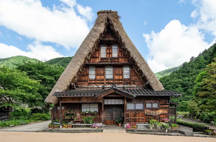 old thatched roof farmhouse surrounded by mountains