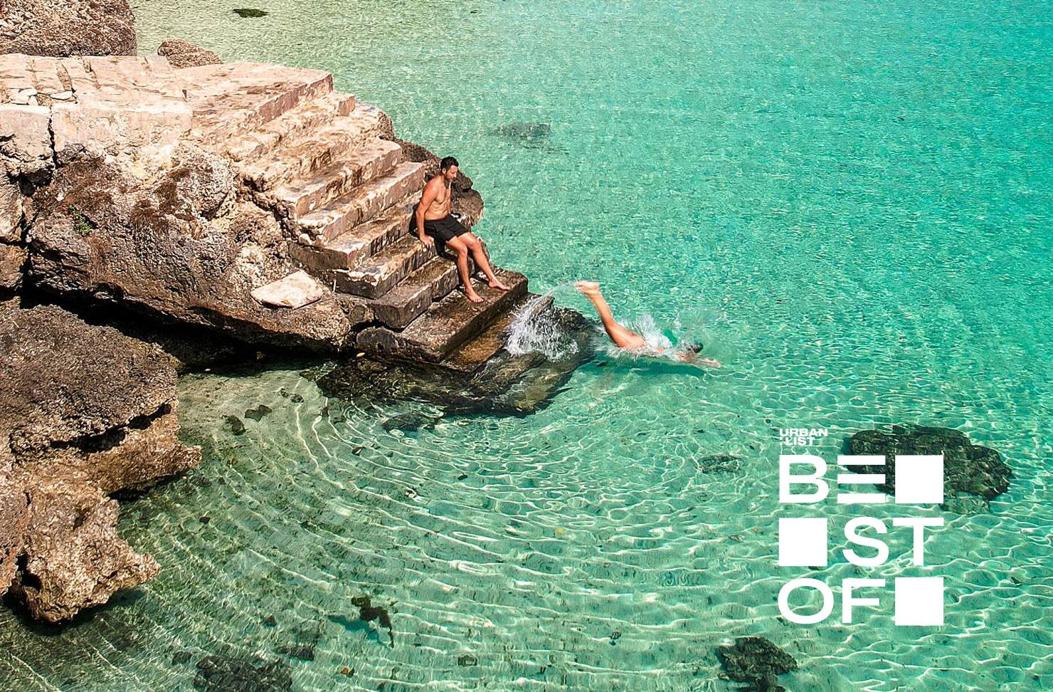 two people on a set of stairs diving into the ocean