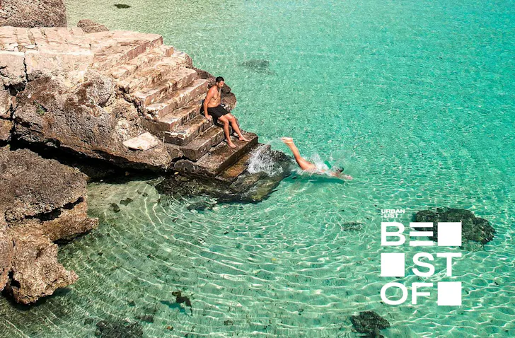 two people on a set of stairs diving into the ocean