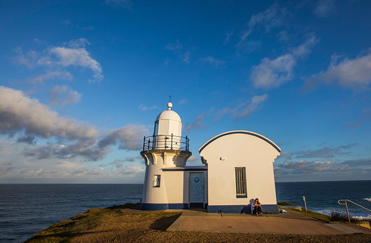 sunset view of tacking point lighthouse with girl sitting in front
