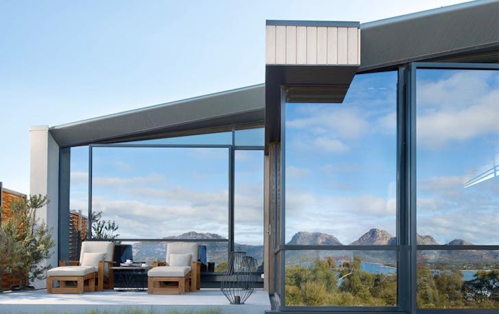 the lake reflects off the exterior of a hotel