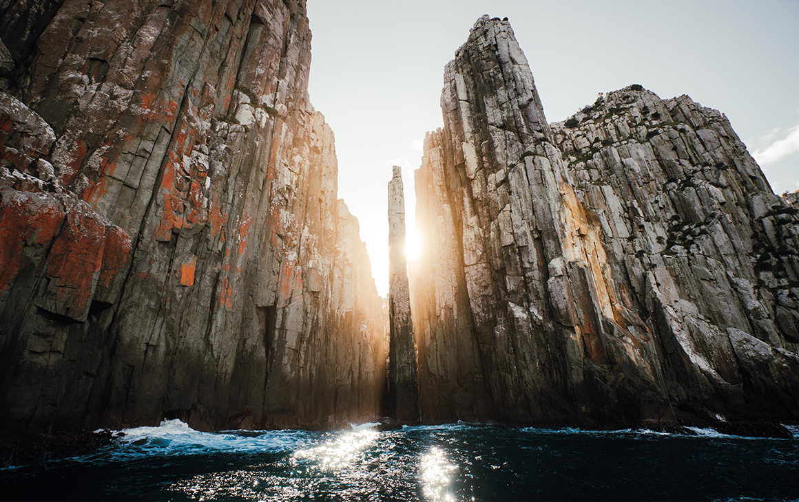 Sunlight streams through the towering cliffs at Tasman National Park