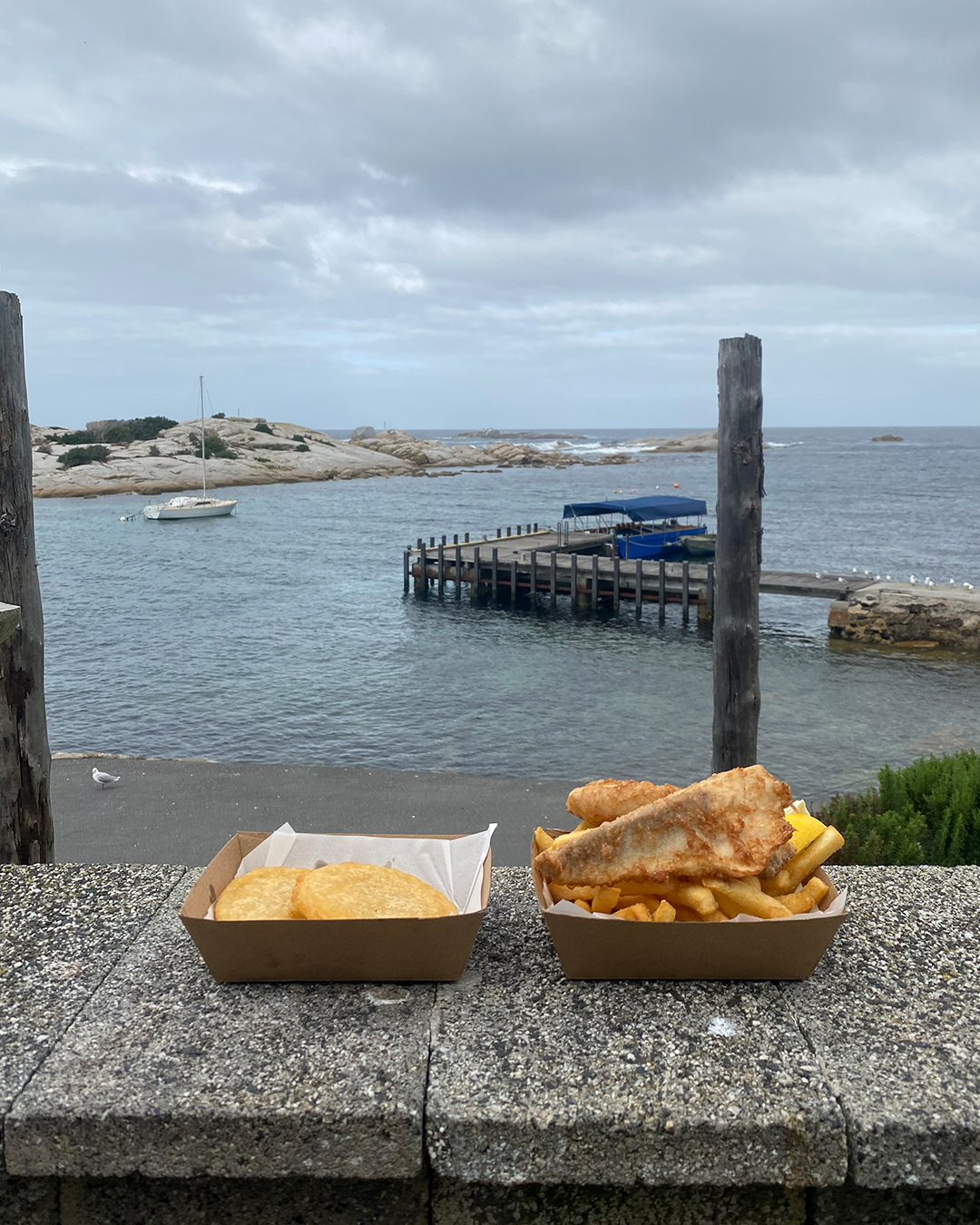 a basket of fish and chips by the ocean