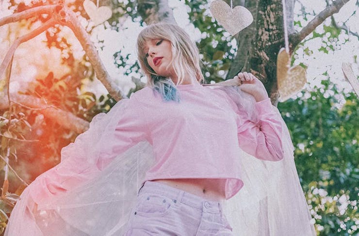 taylor swift dances with the sun setting over trees behind her.