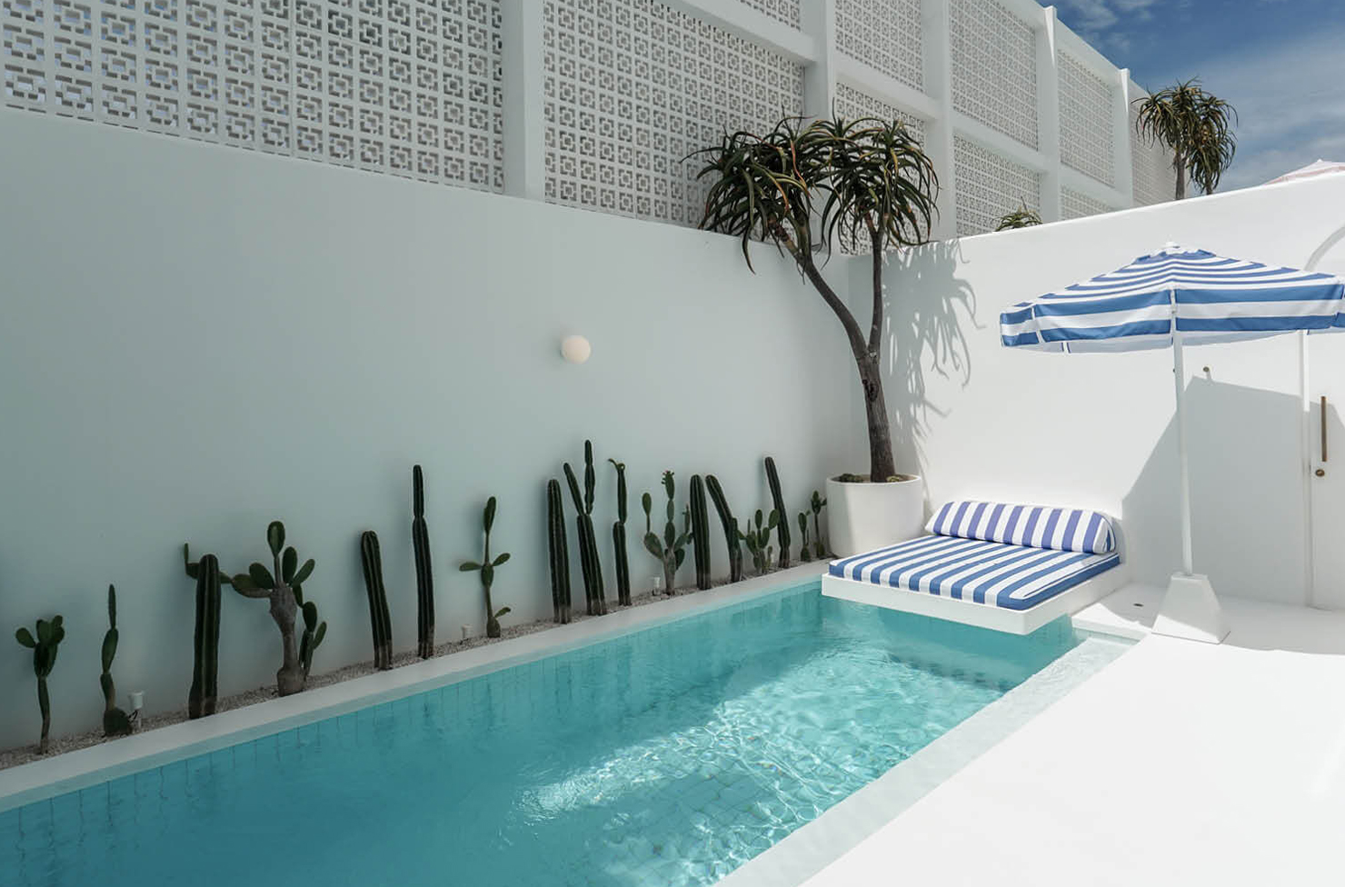 a pool with a blue and white striped umbrella and sun lounge
