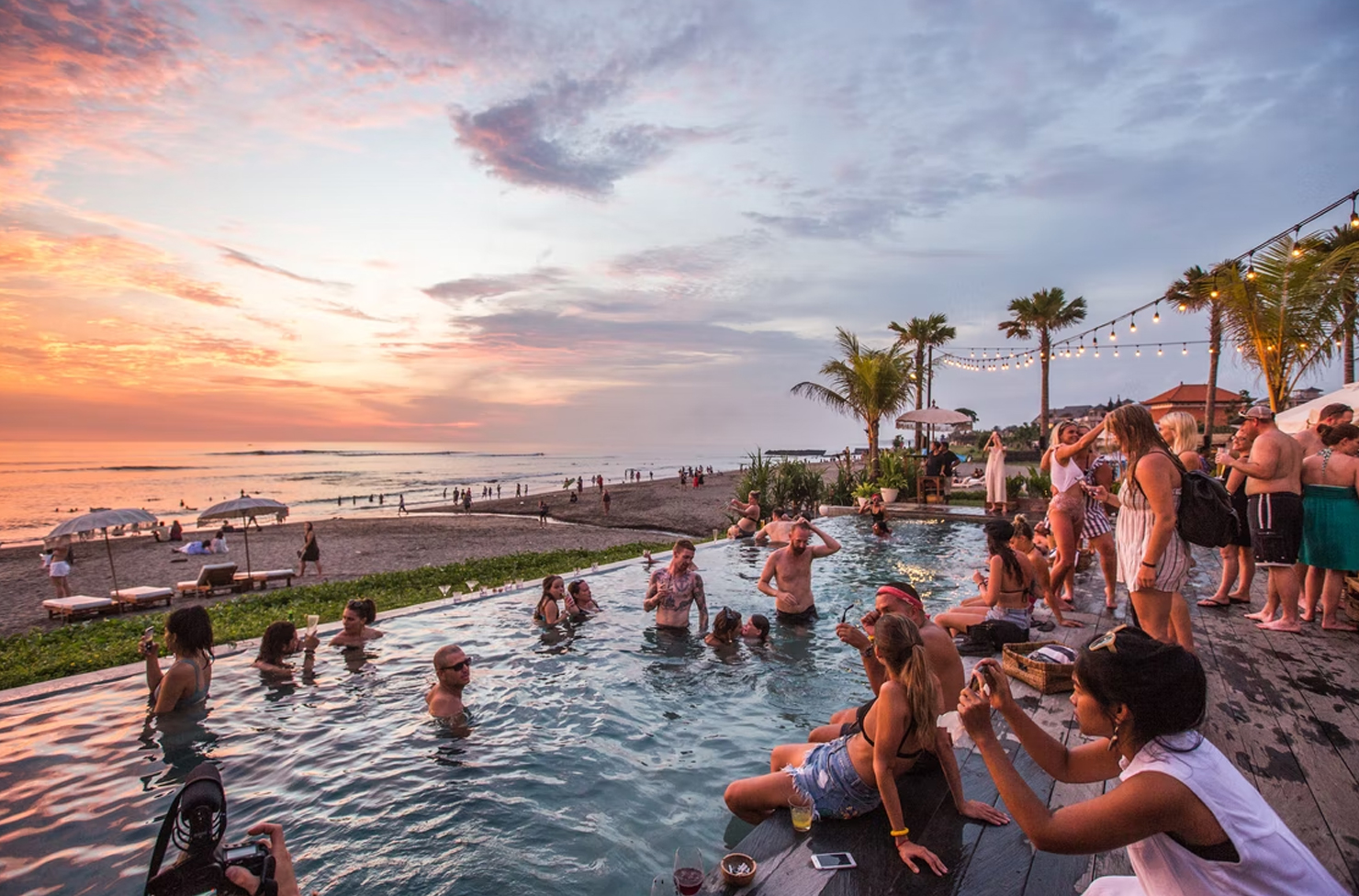 a group of people sitting in a pool watching the sun go down