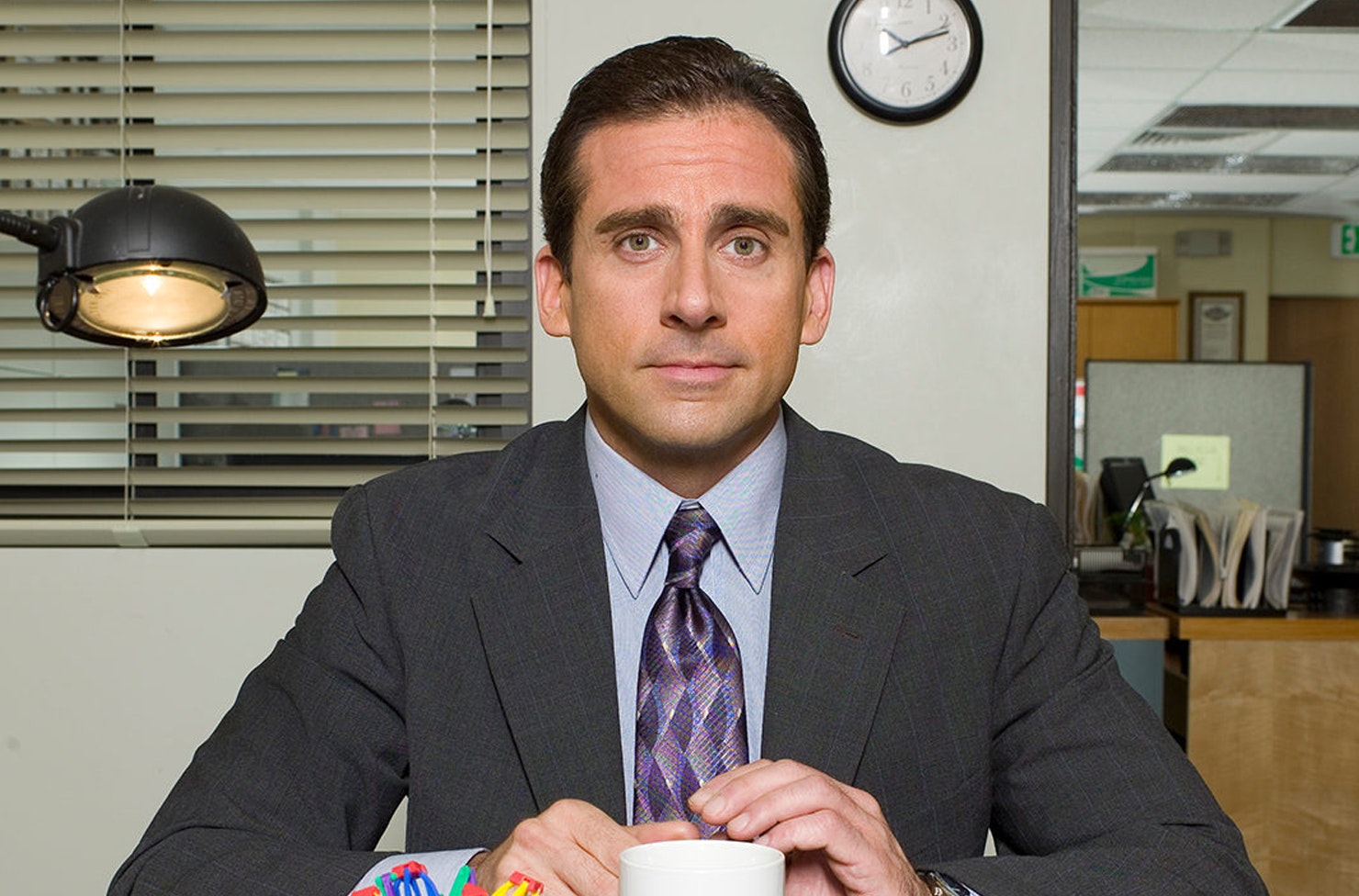 a person sitting at a desk wearing a suit