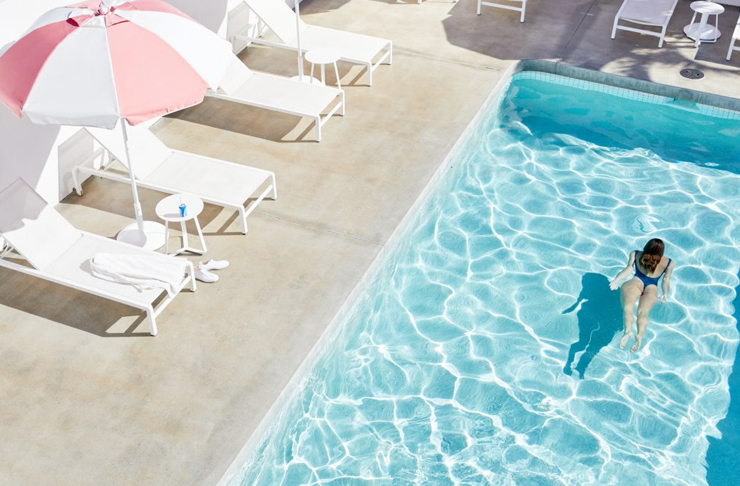 girl swimming underwater in retro pool surrounded by umbrellas