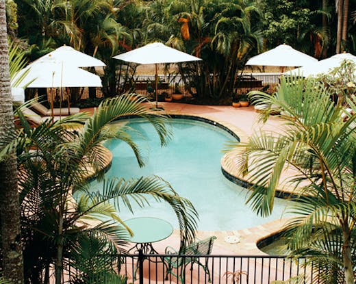 retro kidney shaped pool surrounded by tropical trees