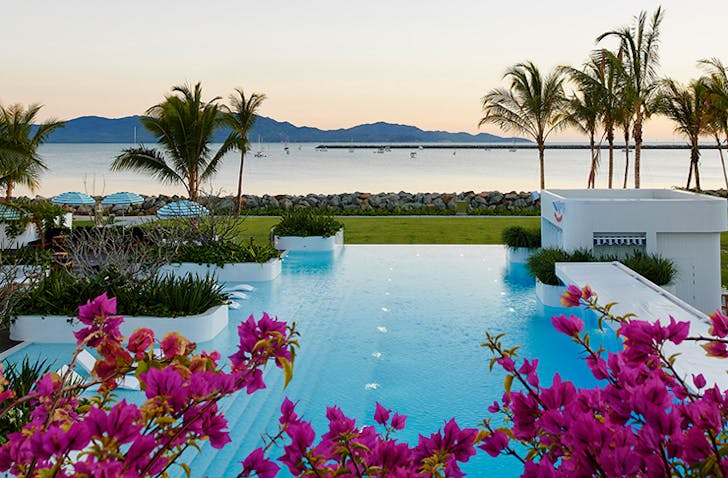 beachside pool surounded by palms and trees