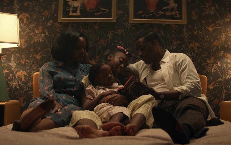 a family cuddles up close on a couch.