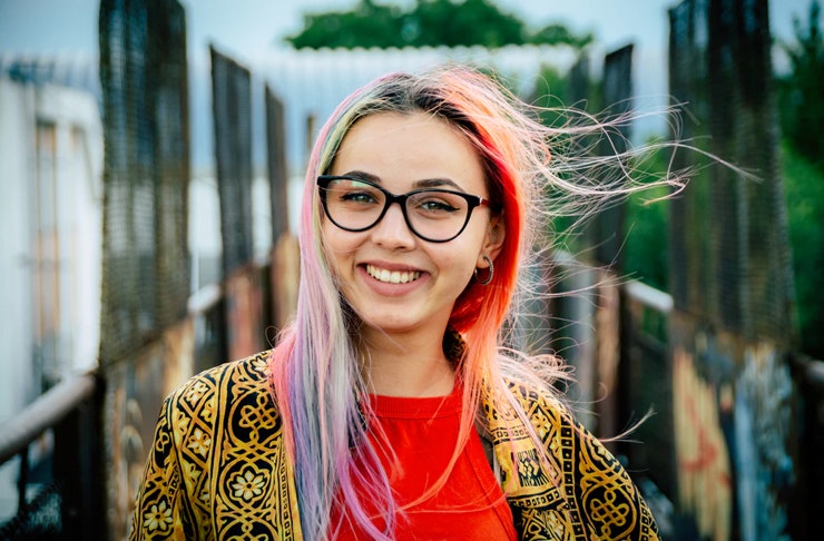 girl wearing glasses and patterned jacket smiling