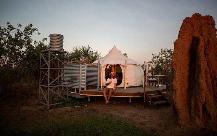a man sits at Top End Safari Camp at dusk
