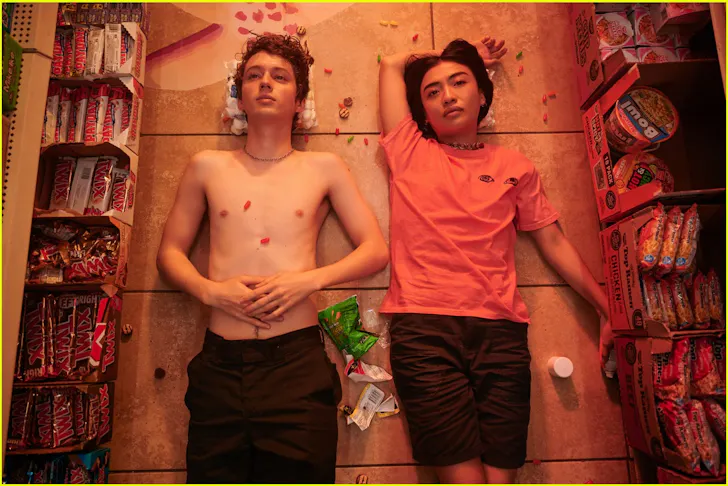 Two people laying on the ground covered in lollies in the film Three Months. 