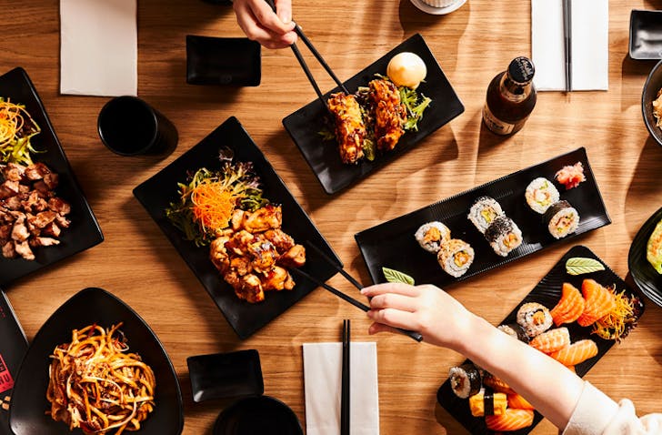 two hands eating food over table