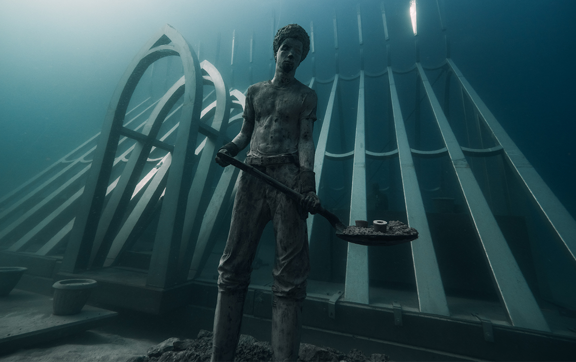 an underwater sculpture featuring a boy holding a shovel.