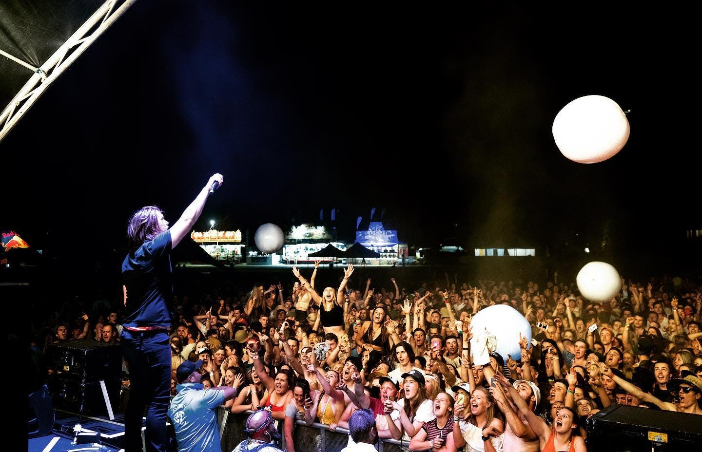 Singer on stage to a crowd of people at Vanfest. 
