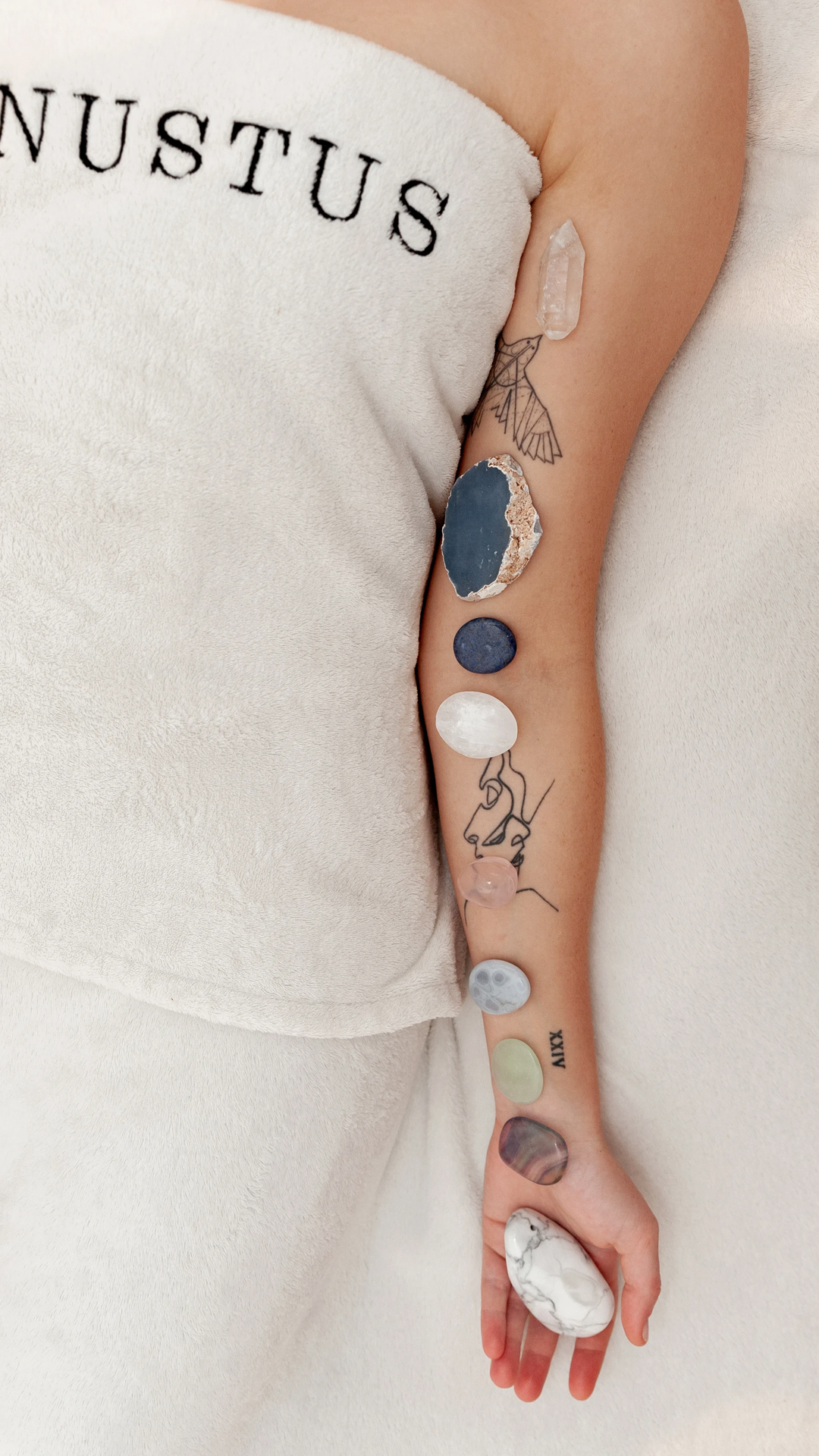 person lying on bed with stones on arm