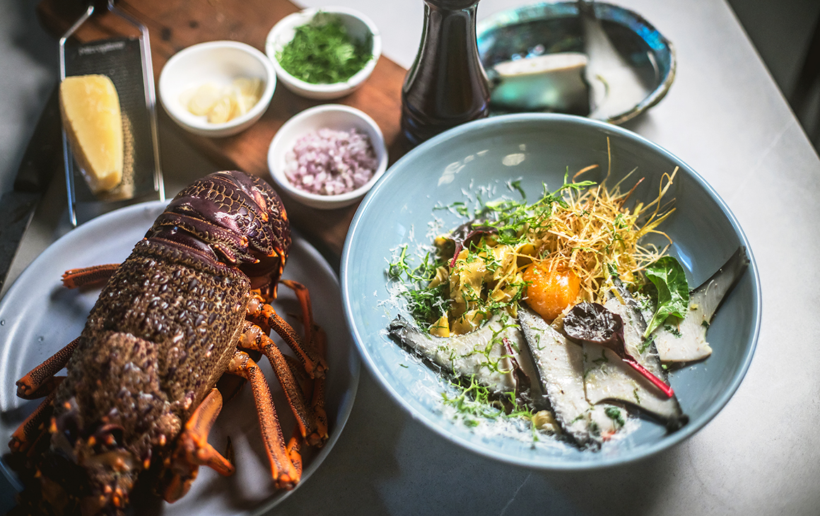 a delicious spread of food on a table including a salad and whole lobster.