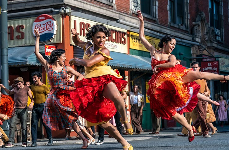 three girls on street dancing in vibrant dresses