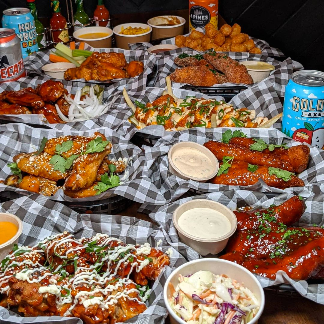 an entire table spread of hot sauce, beer and chicken wings