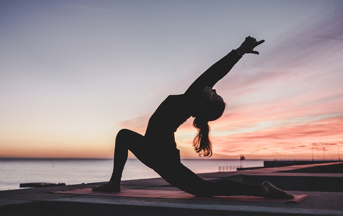 a woman does yoga at sunset