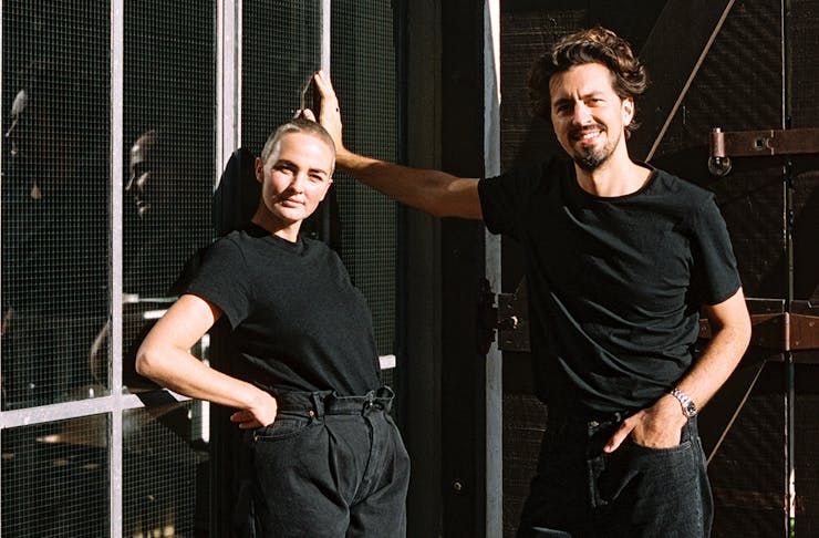 Youswim founders, dressed in black, pose against a wall.